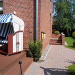Haus mit Strandkorb, gepflastertem Weg und Garten.