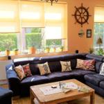 Wohnzimmer mit dunklem Sofa, dekorativen Kissen und Holztisch. An den Wänden hängen ein Ruder und Bilder.