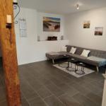 Wohnzimmer mit grauem Sofa, drei runden Tischen und Wandbildern.