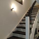 Treppe mit dunklen Stufen und weißem Geländer führt nach oben.