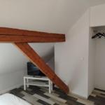 Schlafzimmer mit Holzbalken, Kleiderschrank und TV-Ständer.
