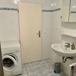Badezimmer mit Waschmaschine, Waschbecken und Spiegel