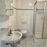Badezimmer mit Dusche, Toilette und Waschbecken mit Spiegel.