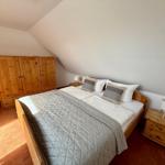 Schlafzimmer mit Holzbett, Nachttischen und Kleiderschrank unter Dachschrägen.