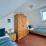 Zimmer mit zwei Betten, Holzschrank und Dachfenster.