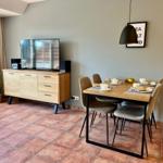 Esszimmer mit Tisch, Stühlen und TV-Schrank. Terrakottafußboden und Wandbild.