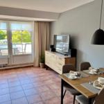 Esszimmer mit Tisch, Stühlen und Fernseher. Terrasse mit Gartenblick.