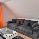 Ein Wohnzimmer mit grauem Sofa, weißem Tisch und orangefarbenen Vorhängen.