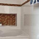 Bad mit weißer Badewanne und farbigen Fliesen an der Wand.