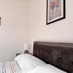 Schlafzimmer mit Bett, Nachttisch und Wandbildern.