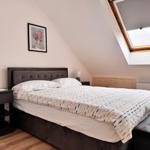 Schlafzimmer mit Dachschrägen, Doppelbett, Nachttischen und Dachfenster.
