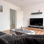 Wohnzimmer mit Fernseher, Couch und Tisch. Wandbild und Schrank sichtbar.