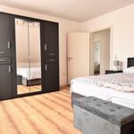 Schlafzimmer mit Bett, Kleiderschrank und Fußbank.