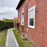 Rotes Backsteinhaus mit Gartenweg und Hecke. Fenster mit weißen Rahmen.