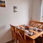 Holztisch mit Stühlen und Fensterbank. Tisch gedeckt mit Obst und Snacks.