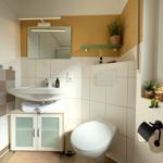 Badezimmer mit Waschbecken, Spiegel, Toilette und Fenster