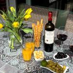 Tisch mit Wein, Orangensaft, Oliven und Tulpen auf einer Mosaikplatte.