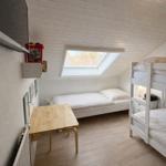 Zimmer mit Doppelstockbett, Einzelbett, Tisch und Dachfenster.