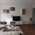 Wohnzimmer mit weißem Sofa, TV-Möbel und Holzboden.