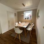 Esszimmer mit Tisch, Stühlen und Fenster. Holzboden und weiße Wände.