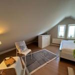 Schlafzimmer mit Dachschräge, Bett, Schrank und zwei Fenstern.