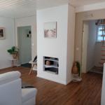 Wohnzimmer mit weißem Sofa, Kamin und Holzboden. Treppe führt zur oberen Etage.