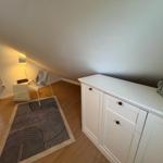 Schlafzimmer mit Dachschräge, weißem Schrank und gemustertem Teppich.