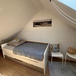 Schlafzimmer mit Dachschrägen, Bett, Stuhl und Tisch.