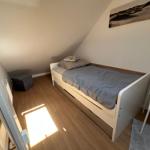 Schlafzimmer mit Dachschrägen, Bett und Stuhl.