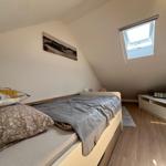 Schlafzimmer mit Dachschräge, Bett, Fenster und Schrank.