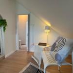 Dachbodenwohnung mit Sitzgelegenheit, Stehlampe und Pflanze.