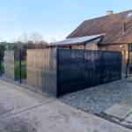 Hinterhof mit Zaun, Kies und Garage neben Haus.