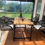 Terrasse mit Holztisch und sechs Stühlen, Blick auf grünen Garten.