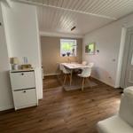 Esszimmer mit Tisch, Stühlen und Fenster. Holzboden und weiße Wände.