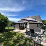 Haus mit Terrasse, Sitzgelegenheiten und Sonnenschirm im Garten