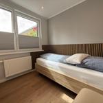 Ein Schlafzimmer mit Bett, Fenster und Holzboden.