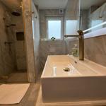 Badezimmer mit Dusche, Waschbecken und Fenster.