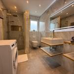 Badezimmer mit Dusche, Waschmaschine und Spiegel