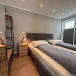 Schlafzimmer mit Doppelbett, Nachttisch und Schrank. Fenster mit Jalousie.