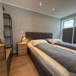 Schlafzimmer mit Doppelbett, Nachttisch und Schreibtisch. Fenster mit Jalousie.