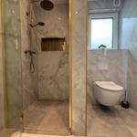 Dusche mit Glaswand und Toilette in Marmoroptik