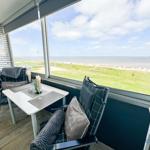 Terrasse mit Tisch und Stühlen. Blick auf Strand und Meer.