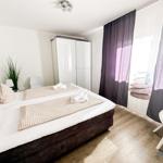 Schlafzimmer mit Doppelbett, Schwebetüren und Vorhängen mit Steinmotiv.