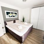 Schlafzimmer mit Doppelbett, Schwebetüren und Wandbild mit Blumen.
