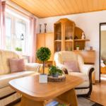 Wohnzimmer mit Sofa, Sessel, Tisch und Holzmöbel. Durchgang zur Schlafzimmer.