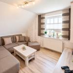 Wohnzimmer mit Sofa, Couchtisch und Fenster mit Jalousie.