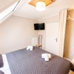 Schlafzimmer mit Dachfenster, Bett, TV und Kleiderschrank.