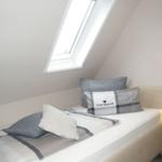 Schlafzimmer mit Dachschrägen, Dachfenster und Bett mit Kissen.