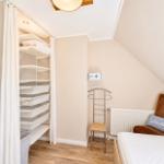 Schlafzimmer mit Kleiderschrank, Bett und Sessel. Dachschrägen und Holzboden.