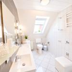 Badezimmer mit Dusche, Toilette und Waschbecken unter Dachschrägen.